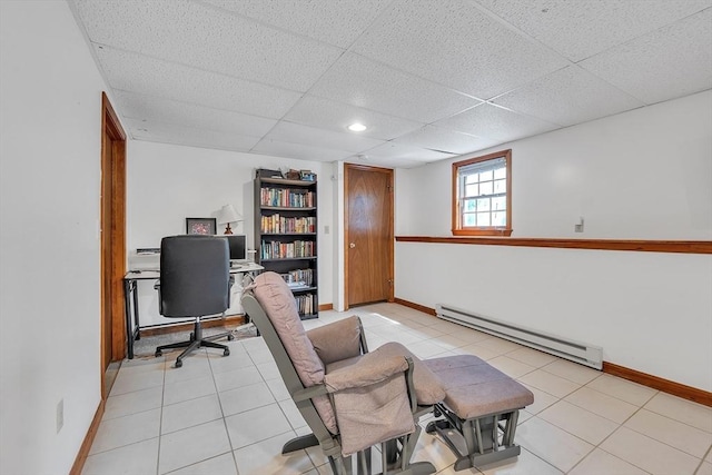 office space with a baseboard heating unit, baseboards, a paneled ceiling, and light tile patterned floors