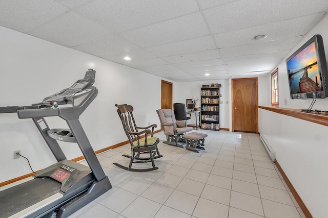 exercise room with baseboard heating, a paneled ceiling, and baseboards
