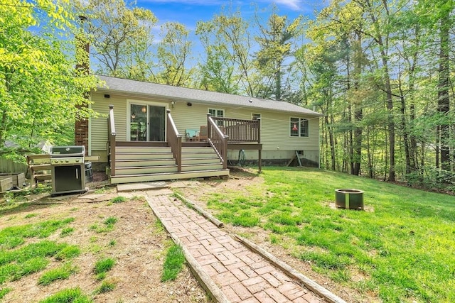 rear view of property with a fire pit, a deck, and a yard