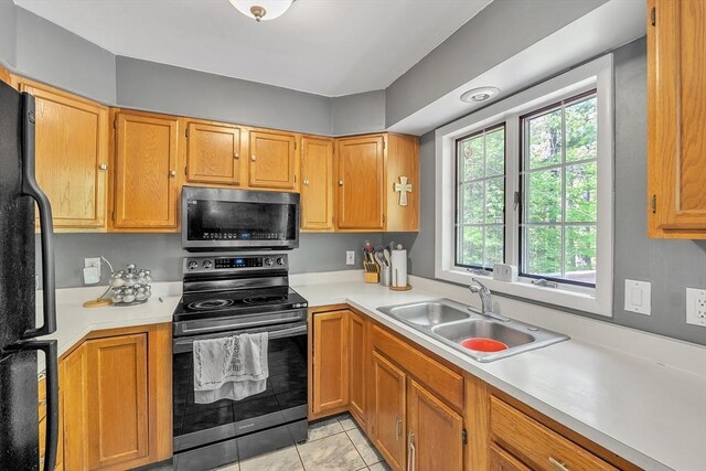 kitchen featuring appliances with stainless steel finishes, a sink, light countertops, and light tile patterned floors