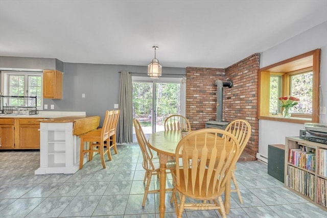 dining space featuring a wood stove, healthy amount of natural light, a baseboard radiator, and light tile patterned flooring