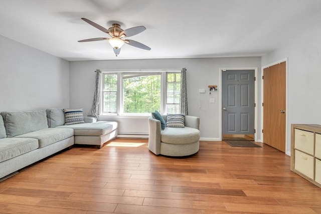 living room featuring a ceiling fan, light wood-style flooring, a baseboard radiator, and baseboards
