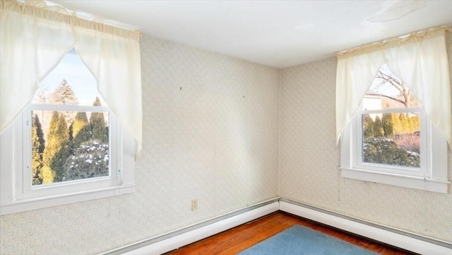 spare room featuring a baseboard heating unit and hardwood / wood-style floors