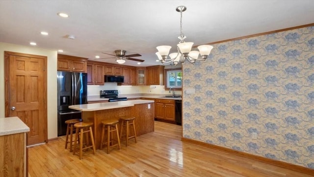 kitchen with a breakfast bar, sink, a center island, light hardwood / wood-style floors, and black appliances