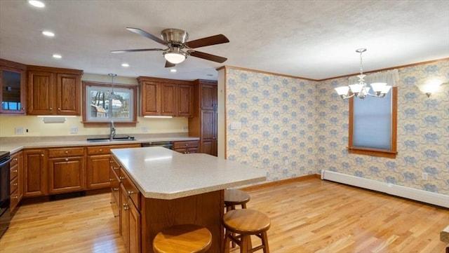 kitchen featuring pendant lighting, sink, crown molding, a center island, and light wood-type flooring