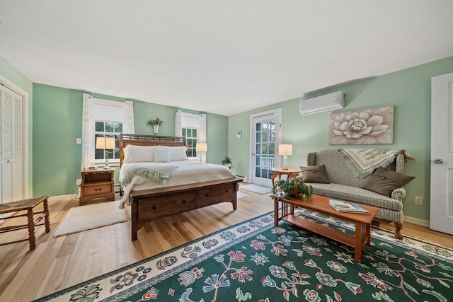 bedroom with a wall mounted air conditioner, hardwood / wood-style floors, and access to outside