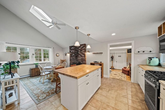 kitchen featuring pendant lighting, butcher block counters, vaulted ceiling with skylight, white cabinetry, and stainless steel appliances