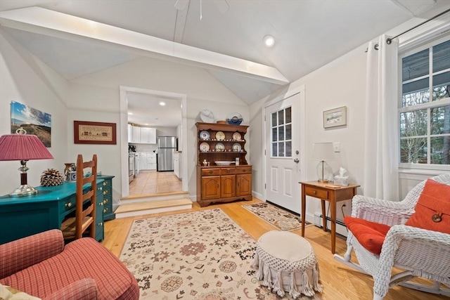 living area featuring light wood-type flooring, vaulted ceiling, and baseboard heating