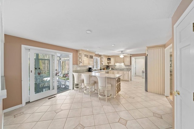 kitchen featuring tasteful backsplash, visible vents, a breakfast bar, a peninsula, and light countertops