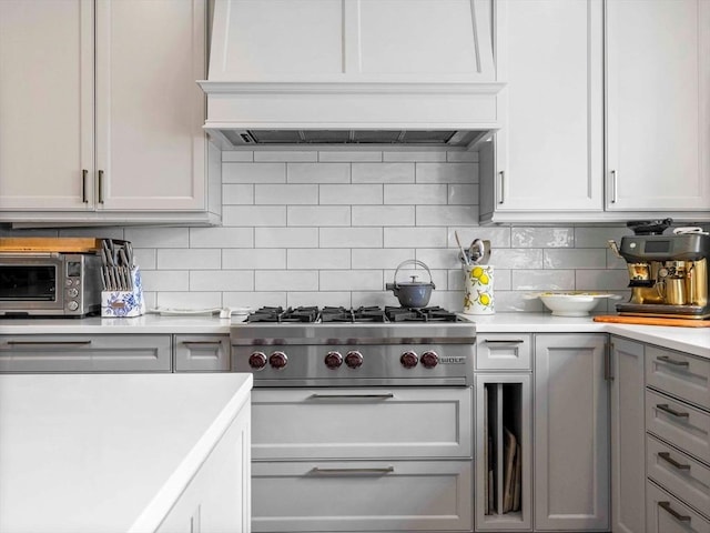 90 Burr Dr, Needham, MA 02492 - kitchen with stainless steel gas stovetop, light countertops, decorative backsplash, and custom range hood
