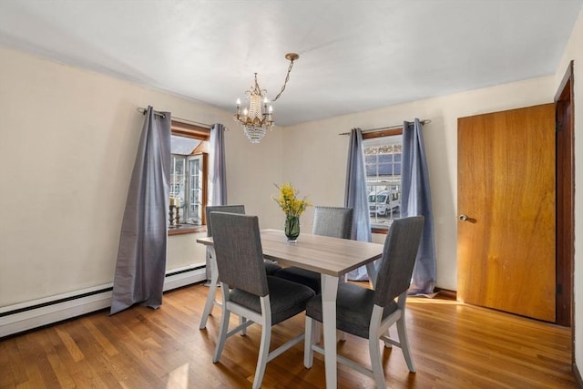 dining area with light hardwood / wood-style floors, an inviting chandelier, and a baseboard heating unit