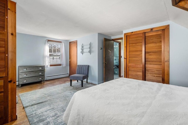 bedroom with baseboard heating, lofted ceiling, and hardwood / wood-style flooring