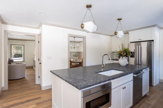 kitchen with an island with sink, appliances with stainless steel finishes, sink, and white cabinets