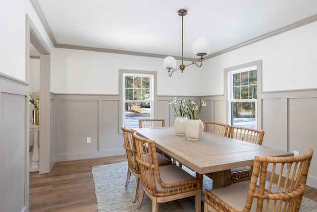 dining area with ornamental molding, wood-type flooring, a chandelier, and a wealth of natural light