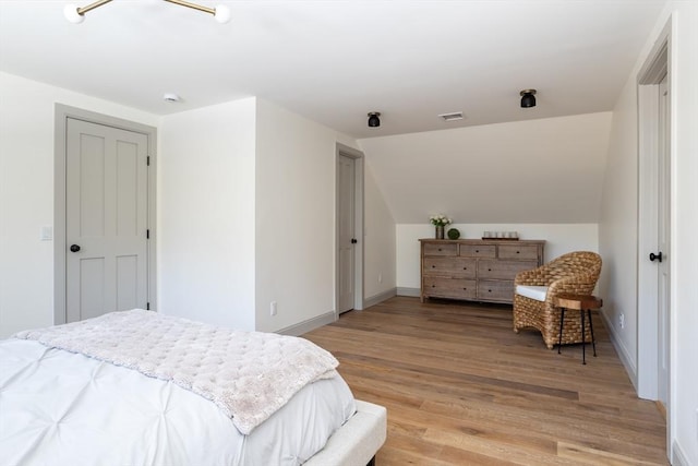 bedroom with lofted ceiling and wood-type flooring