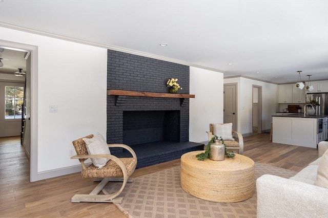 living room with crown molding, light hardwood / wood-style floors, and a brick fireplace