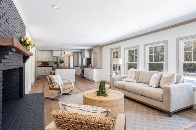 living room with ornamental molding, a brick fireplace, and light hardwood / wood-style flooring