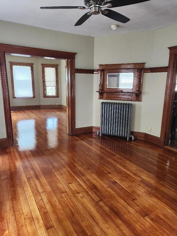 67 Gardner, Boston, MA 02132 - unfurnished living room with radiator, ceiling fan, hardwood / wood-style flooring, and baseboards