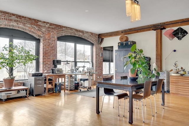 dining space with wood finished floors, brick wall, and beamed ceiling