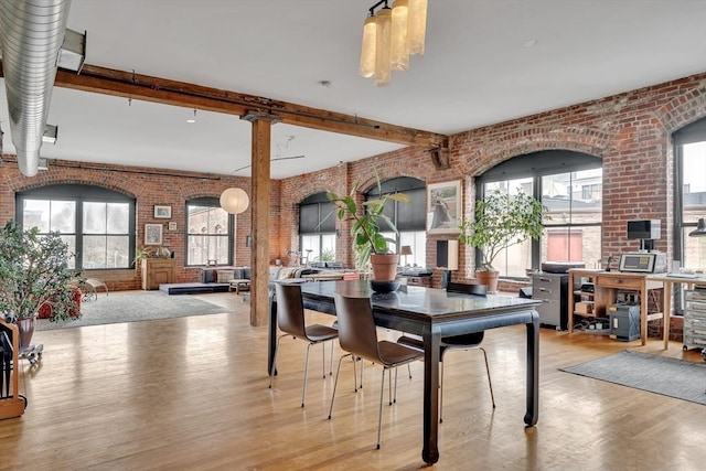 dining room with brick wall, plenty of natural light, and wood finished floors