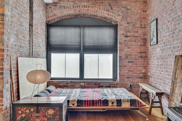 sitting room featuring brick wall and wood finished floors