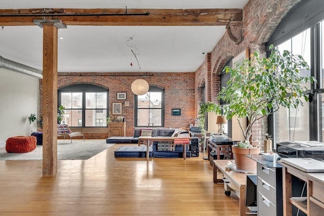 interior space featuring brick wall, light wood-style flooring, and healthy amount of natural light