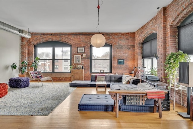 living area featuring plenty of natural light, brick wall, and wood finished floors