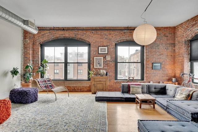 living area featuring brick wall and wood finished floors