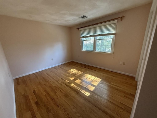 empty room with visible vents, baseboards, and wood finished floors