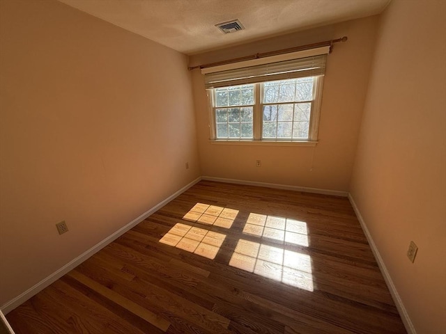 unfurnished room featuring visible vents, a textured ceiling, baseboards, and wood finished floors