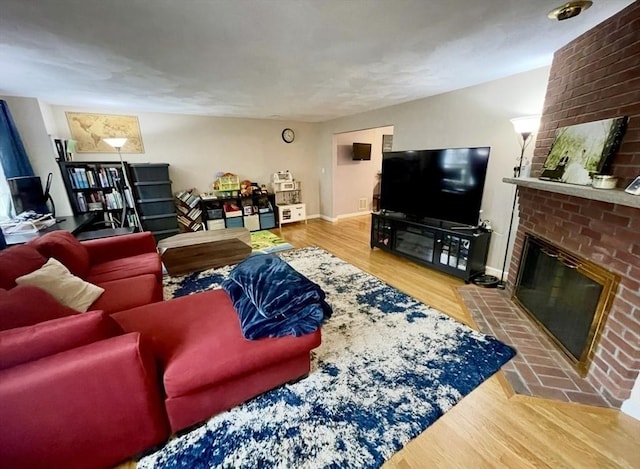 living area with a brick fireplace, wood finished floors, and baseboards