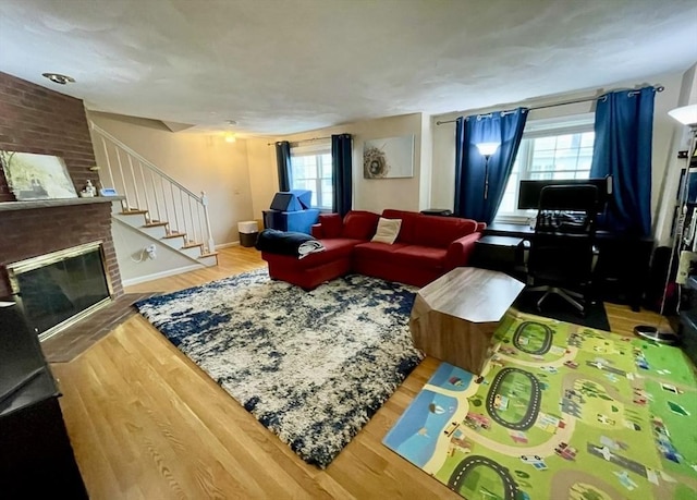 living room featuring stairway, a fireplace, baseboards, and wood finished floors