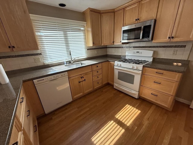 kitchen featuring white appliances, wood finished floors, light brown cabinets, a sink, and decorative backsplash