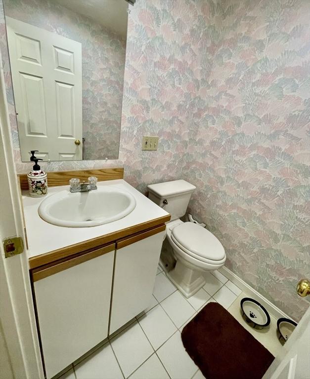 half bath featuring wallpapered walls, toilet, vanity, and tile patterned flooring