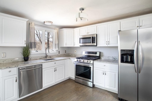 kitchen featuring white cabinets, dark wood finished floors, light stone counters, stainless steel appliances, and a sink