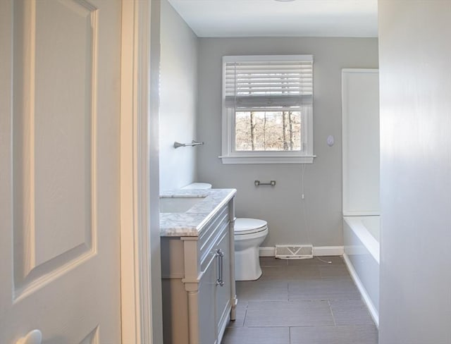 full bath featuring toilet, a washtub, vanity, visible vents, and baseboards