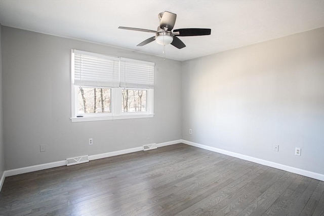 empty room with dark wood-style floors, visible vents, baseboards, and a ceiling fan