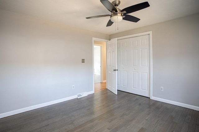 unfurnished bedroom featuring ceiling fan, visible vents, baseboards, a closet, and dark wood finished floors