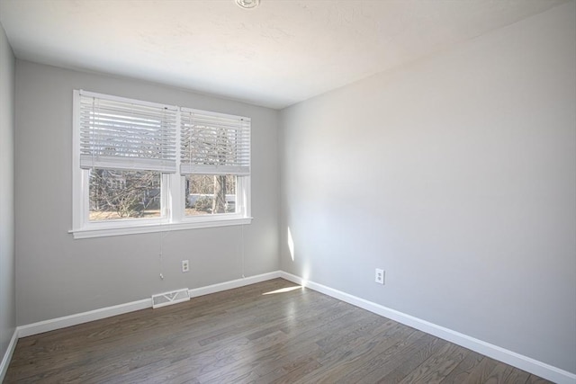 spare room with visible vents, baseboards, and wood finished floors