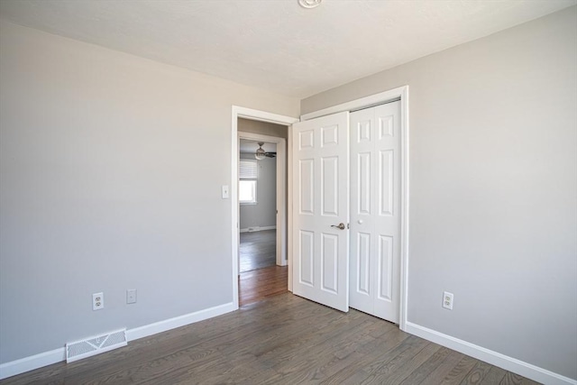 unfurnished bedroom with a closet, visible vents, baseboards, and wood finished floors