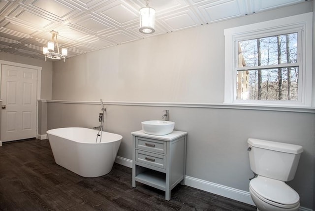 bathroom featuring toilet, a soaking tub, an ornate ceiling, and baseboards