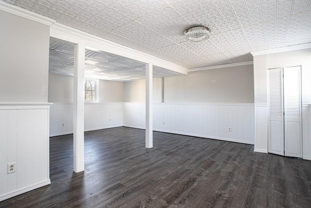 basement featuring a wainscoted wall, an ornate ceiling, and dark wood-type flooring