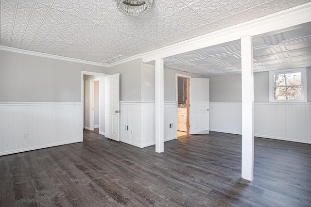 interior space featuring dark wood-style floors, an ornate ceiling, ornamental molding, and wainscoting