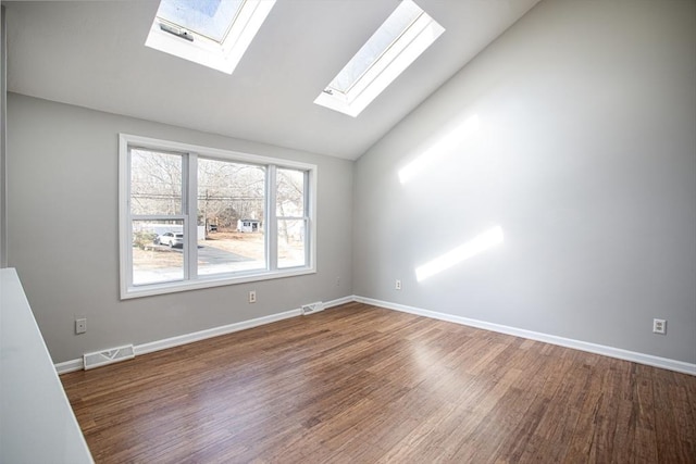 spare room featuring lofted ceiling, wood finished floors, visible vents, and baseboards