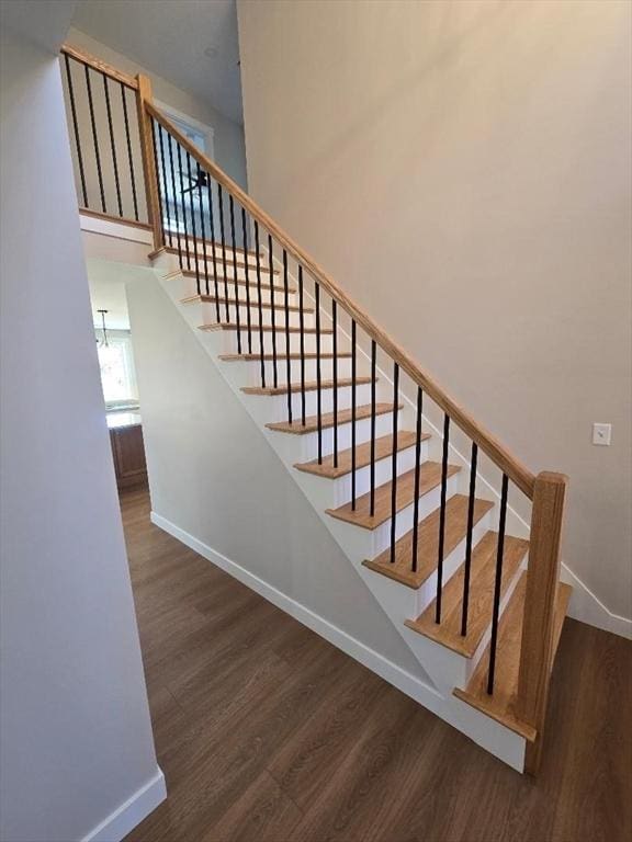 stairway featuring wood-type flooring and a high ceiling