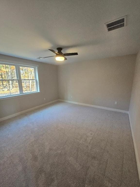 carpeted spare room featuring ceiling fan and a textured ceiling