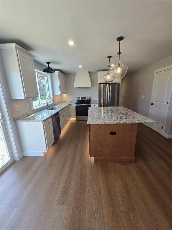 kitchen with white cabinetry, appliances with stainless steel finishes, a center island, and custom range hood