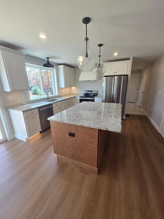 kitchen featuring sink, white cabinetry, stainless steel appliances, a kitchen island, and decorative light fixtures