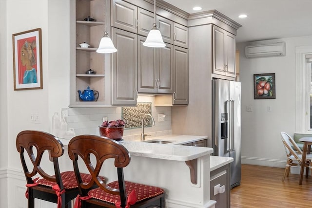 kitchen with a sink, a breakfast bar area, an AC wall unit, high end refrigerator, and open shelves