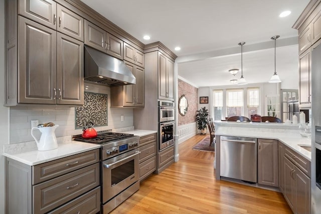 kitchen with under cabinet range hood, stainless steel appliances, light wood-type flooring, and light countertops